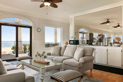 large room with tables, couches and food counter, doors leading to the boardwalk, beach, ocean
