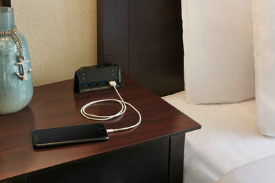 phone charging on hotel table next to bed
